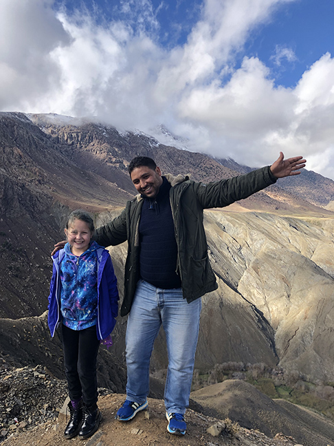 a man and little girl spreading their arms at the top of a mountain range
