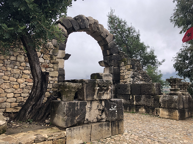 A ruined Roman arch with trees on each side
