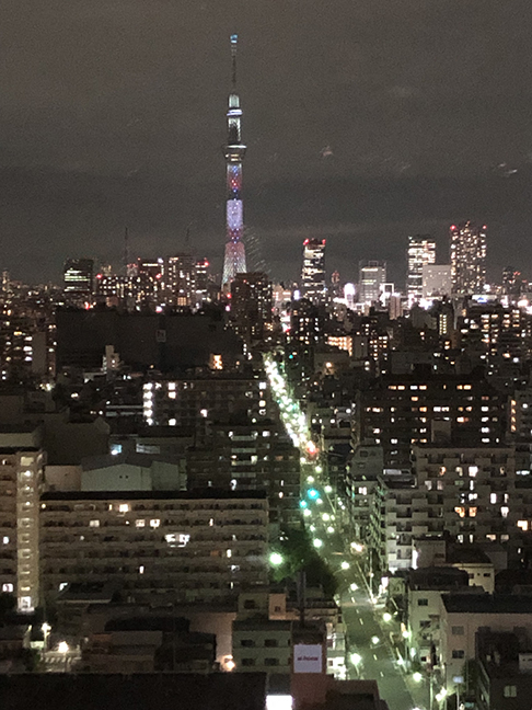 a very tall tower over a city, lit up in purple and pink
