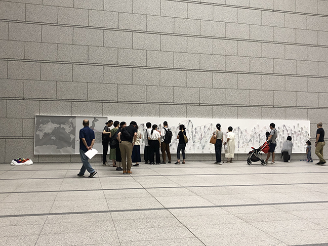 a large space with a rectangle of white hanging on the wall with many strings across it.