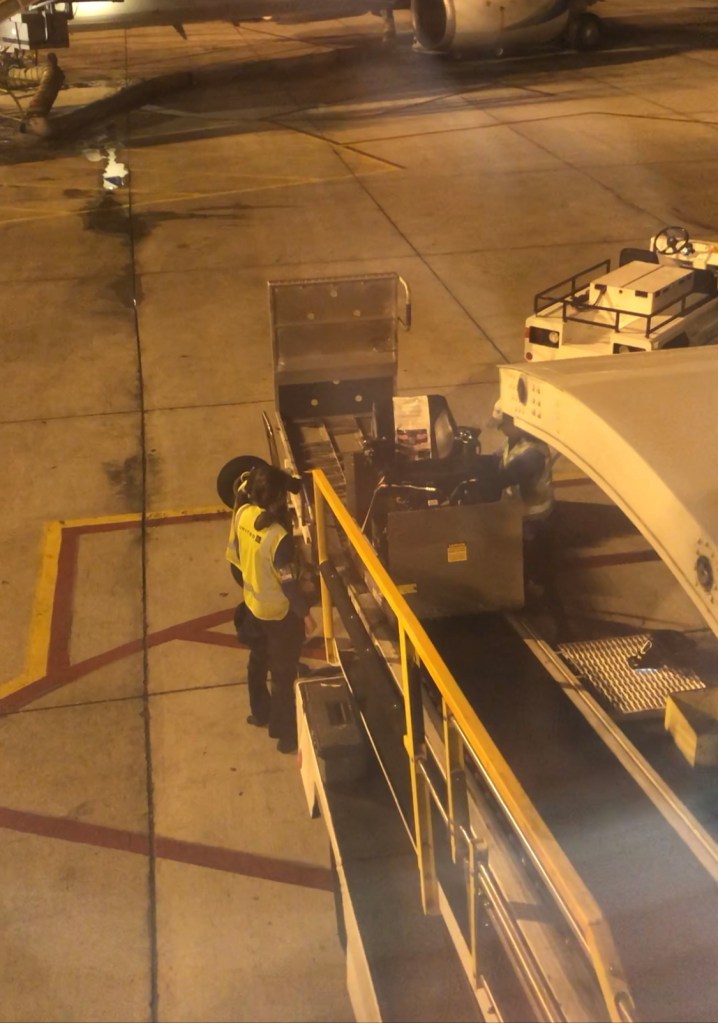 a wheelchair is being taken up a conveyor belt onto a plane

