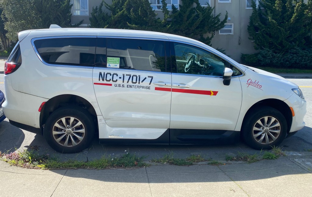 a white wheelchair van with stickers on it that make it look like a Star Trek Galileo shuttle