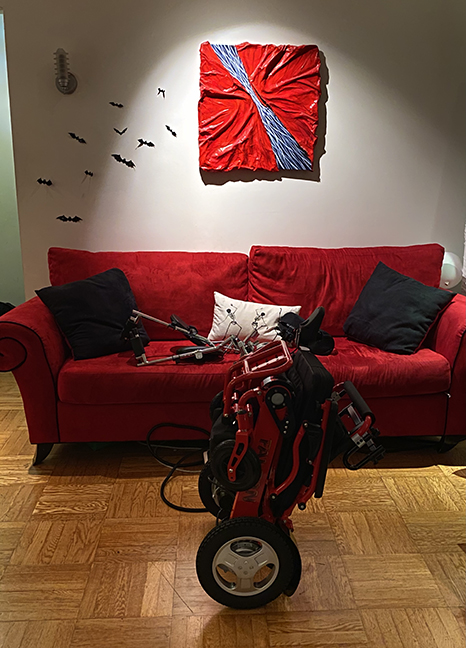 red wheelchair folded up in front of a red couch
