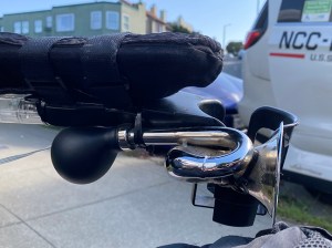 a clown horn and cupholder attached to a wheelchair arm. 
