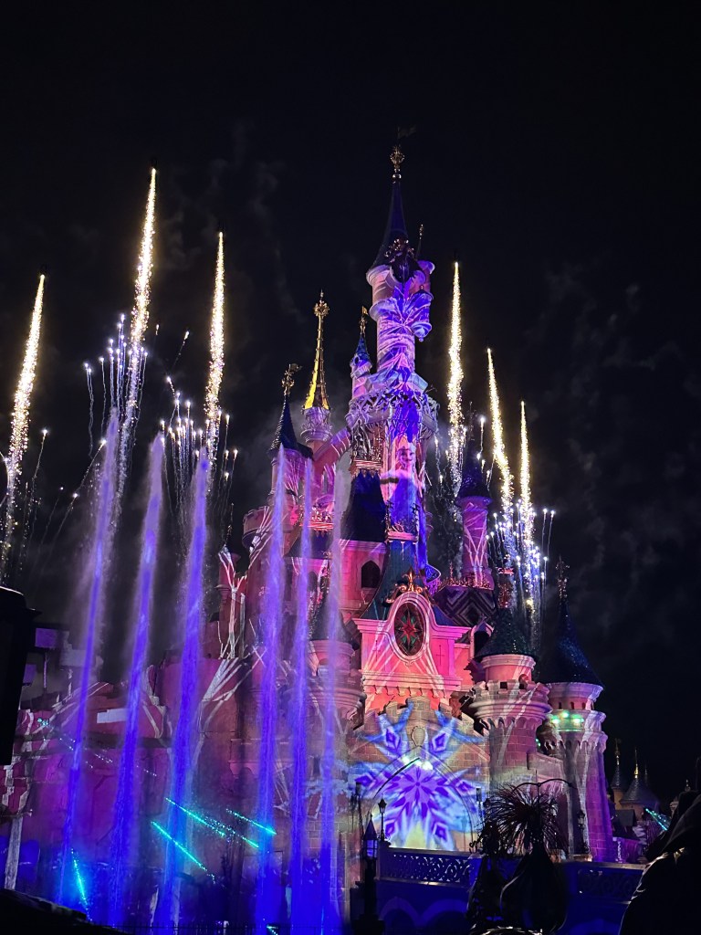 Image os the castle with projections on it, fireworks behind it and water jets and lasers in front of it.  Also a snowflake projected on the front.