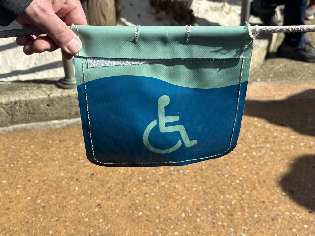 A blue handicapped/wheelchair sign on a badge on a rope