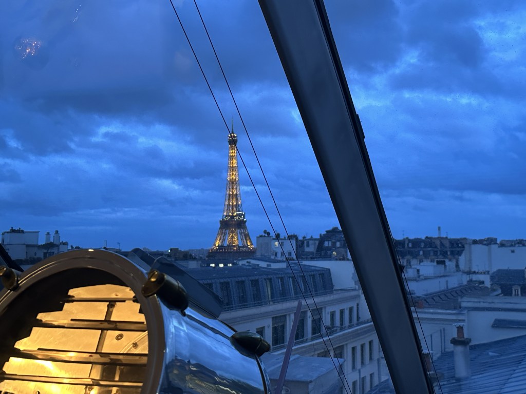 A view of the riffle tower through a curved window with a searchlight in the foreground.