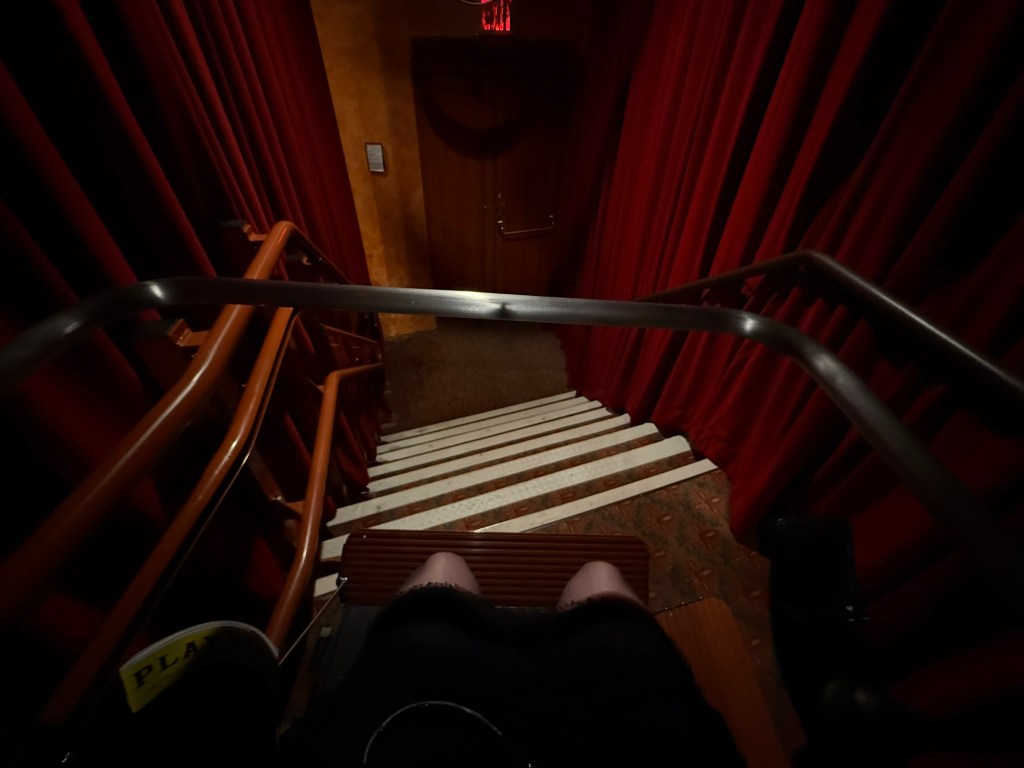 a picture of a wheelchair lift over stairs from the perspective of the person in it.
